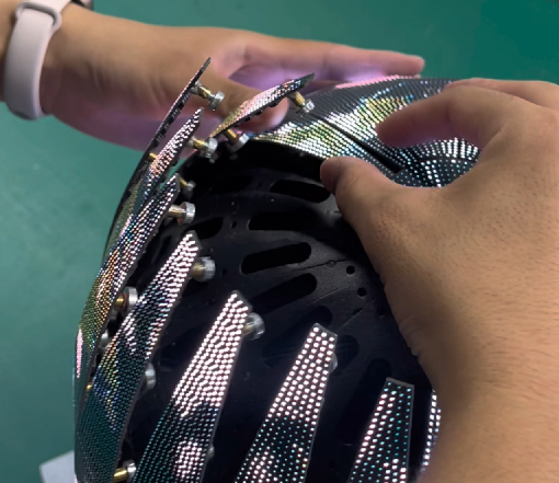 Hands adjusting spherical LED display module with magnetic mount for smooth curved surface installation. Innovative spherical LED screen technology by Ocolour.