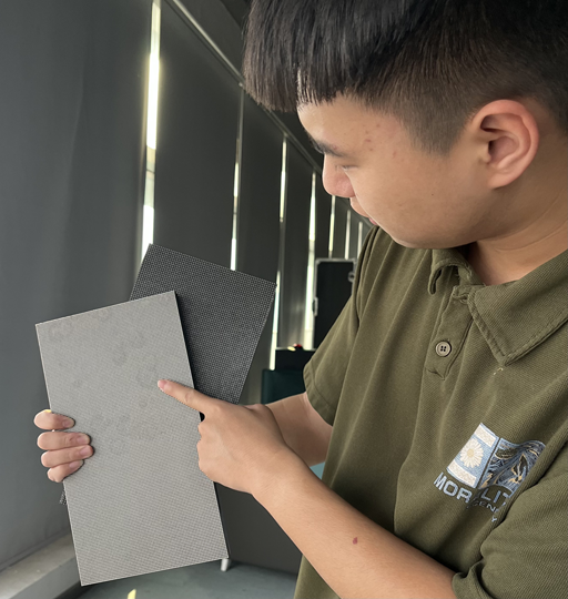 A technician comparing two LED display modules with different pixel pitches to demonstrate how pixel density affects viewing clarity.